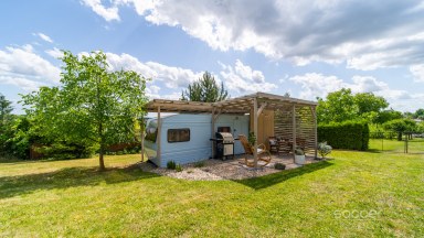 Příjemná venkovská zahrada s rekreačním karavanem a terasou.